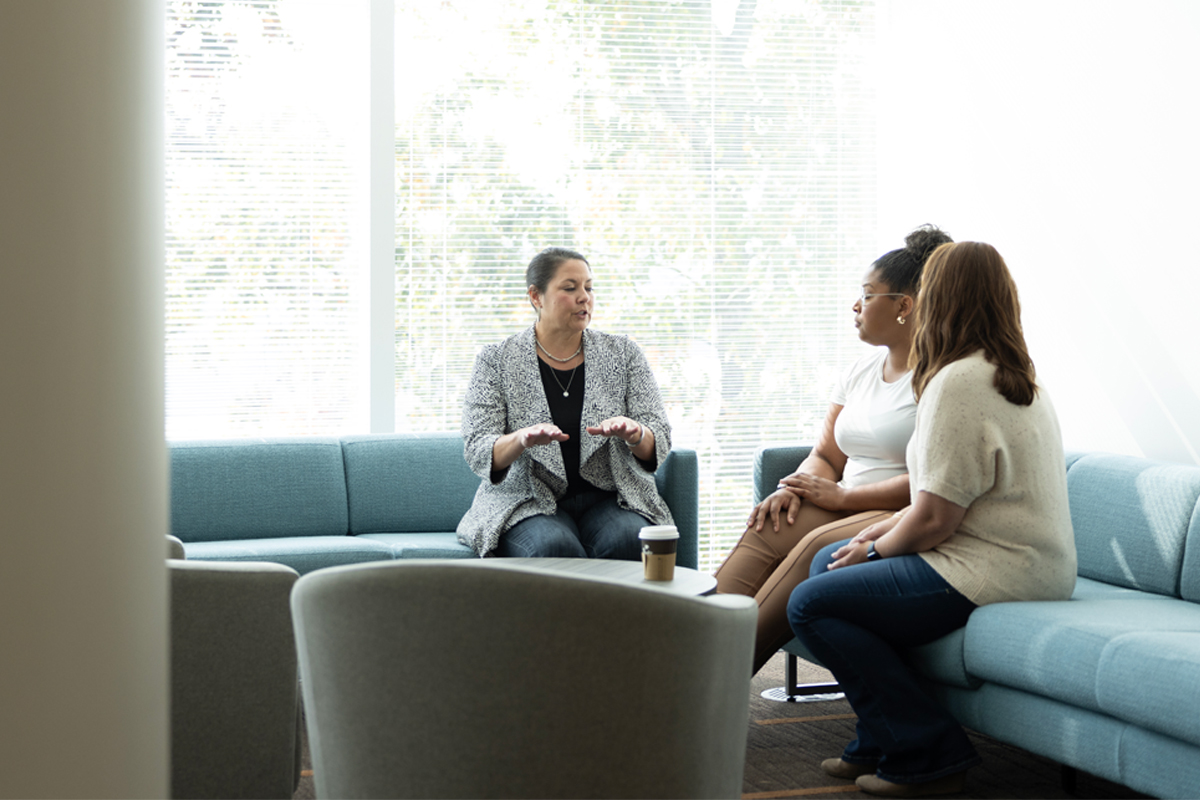 Three women discussing a project in a casual office setting.