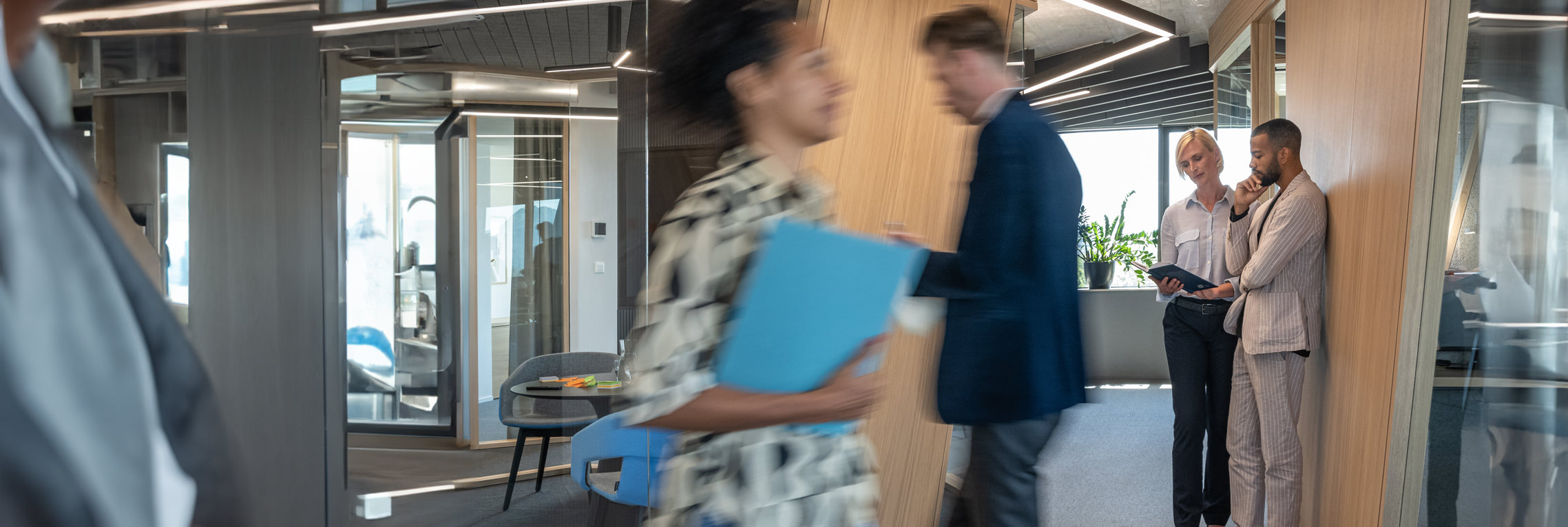 Two employees blurred in movement while two other employees focus on an opened book.