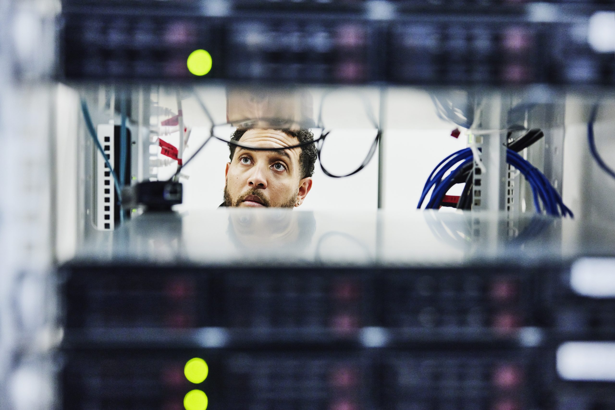A man reviewing technical information on dual computer screens.